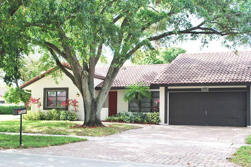 A large white house with a tiled roof and palm trees in front of it.