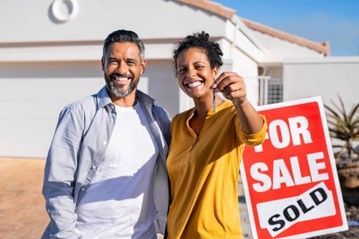 A man and a woman are holding the keys to their new house.