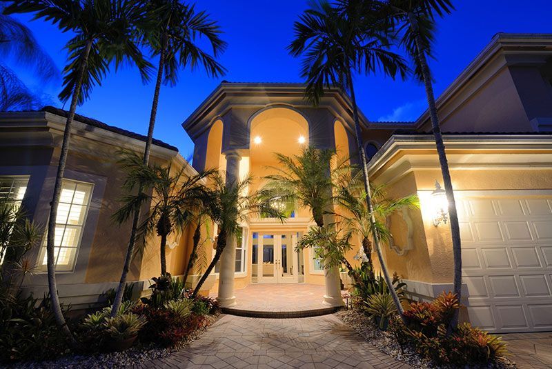 A large white house with a tiled roof and palm trees in front of it.