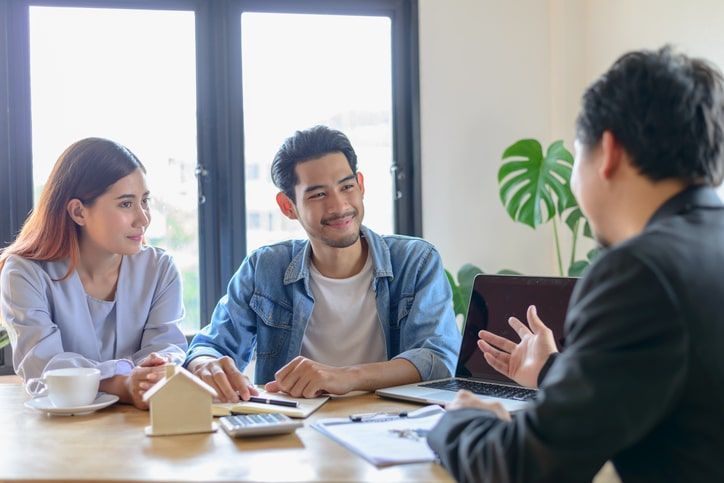 A man and a woman are sitting at a table talking to a real estate agent.