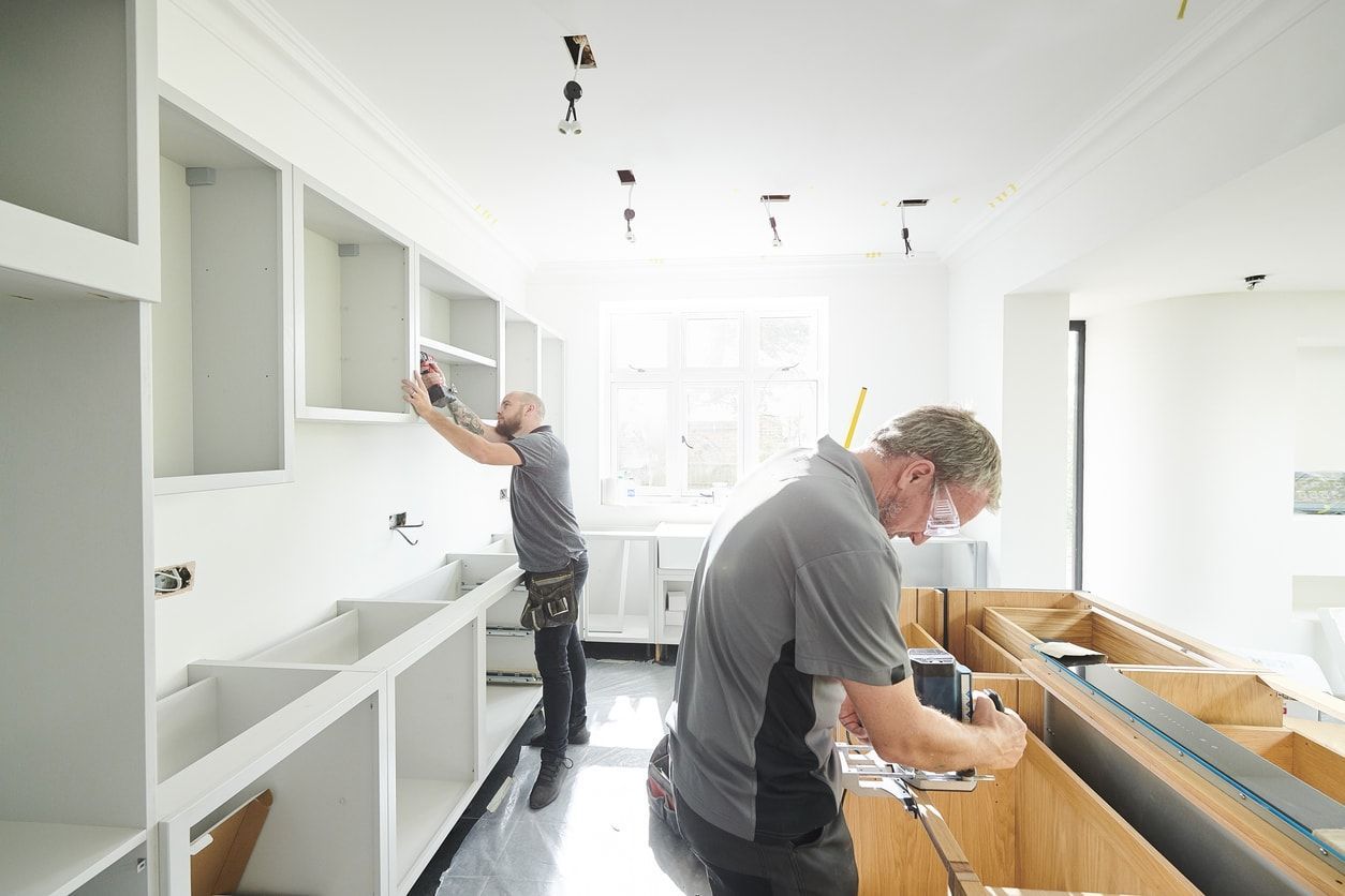 A couple of men are working on a kitchen.