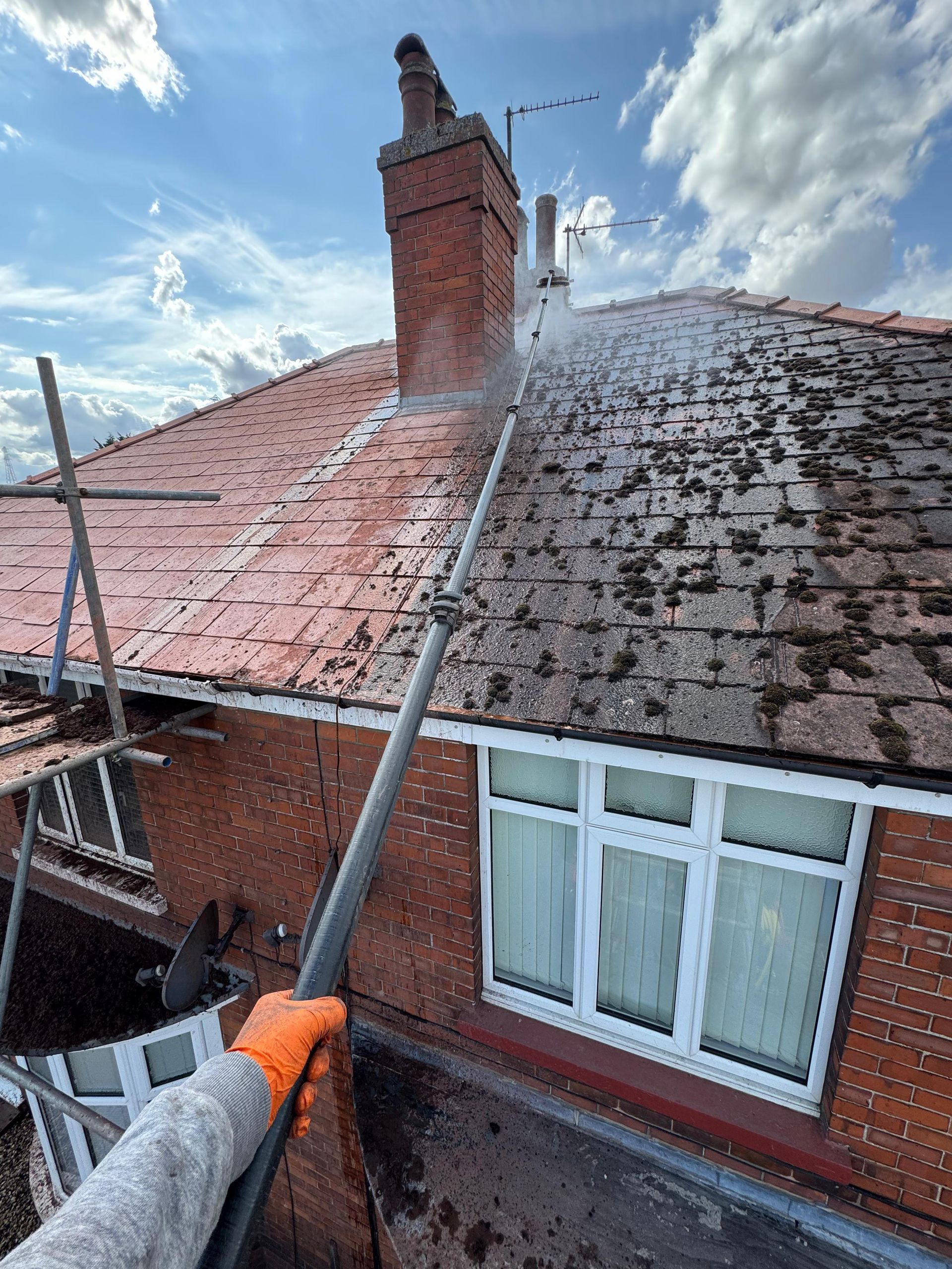 Cleaner washing large house windows under bright spring sunlight