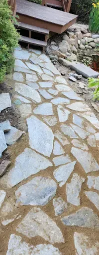 A person is laying bricks on a gravel path.