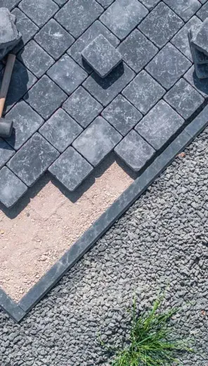 A person is laying bricks on a gravel path.