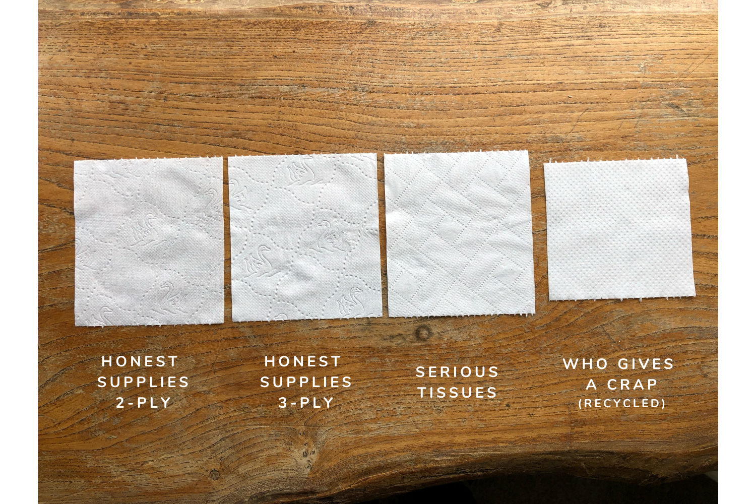 four squares of toilet paper are sitting on a wooden table .