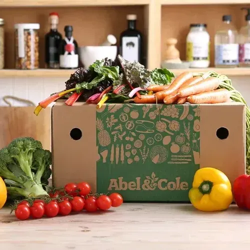 a box of vegetables from abel & cole is sitting on a table .