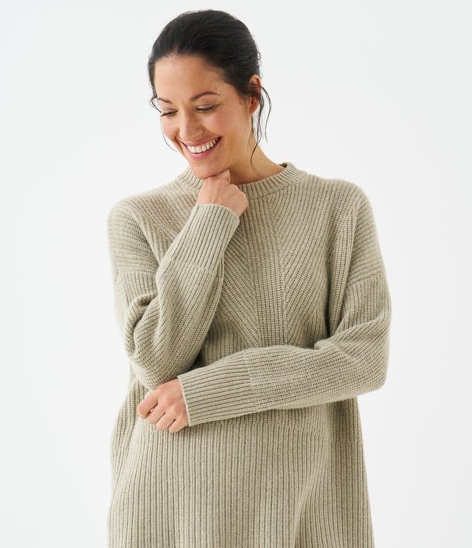 a woman is wearing a wool sweater and smiling .