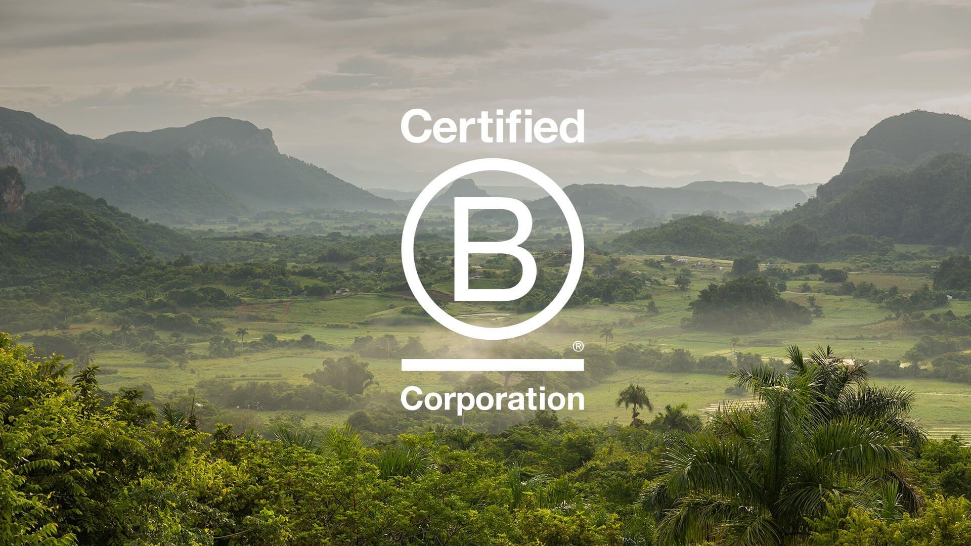 A picture of a certified b corporation logo with mountains in the background.