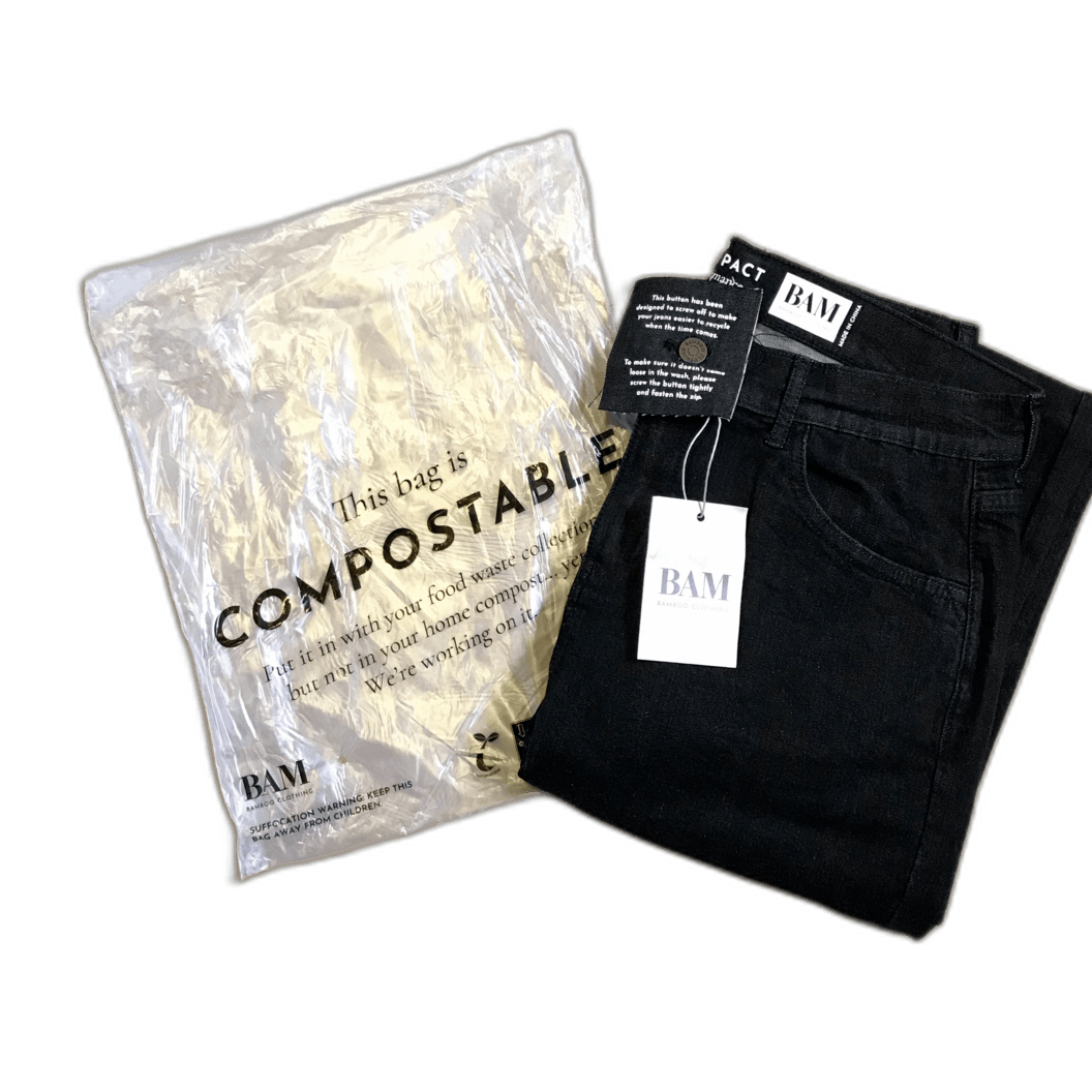 A pair of black jeans sitting next to a compostable bag.