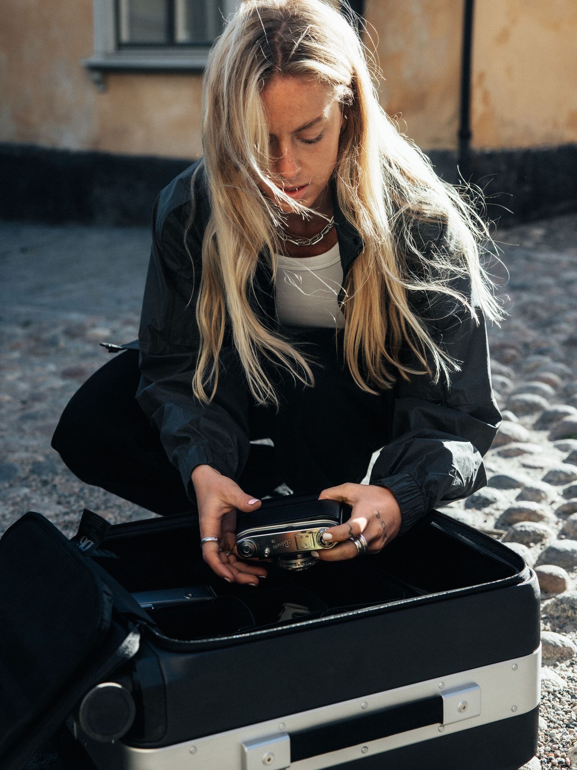 woman with blonde hair getting a camera out of a black suitcase
