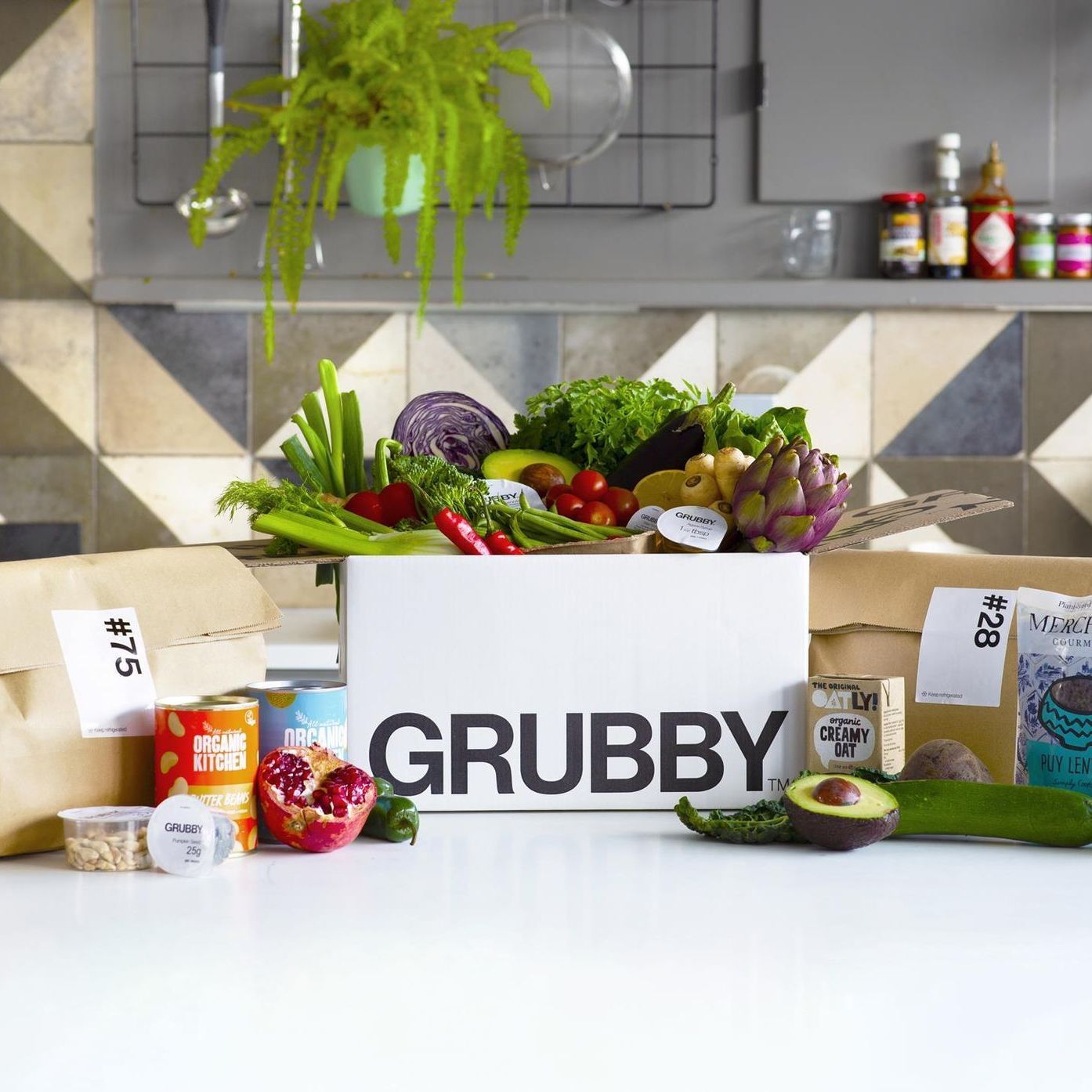 A box filled with vegetables and bread is sitting on a wooden table.