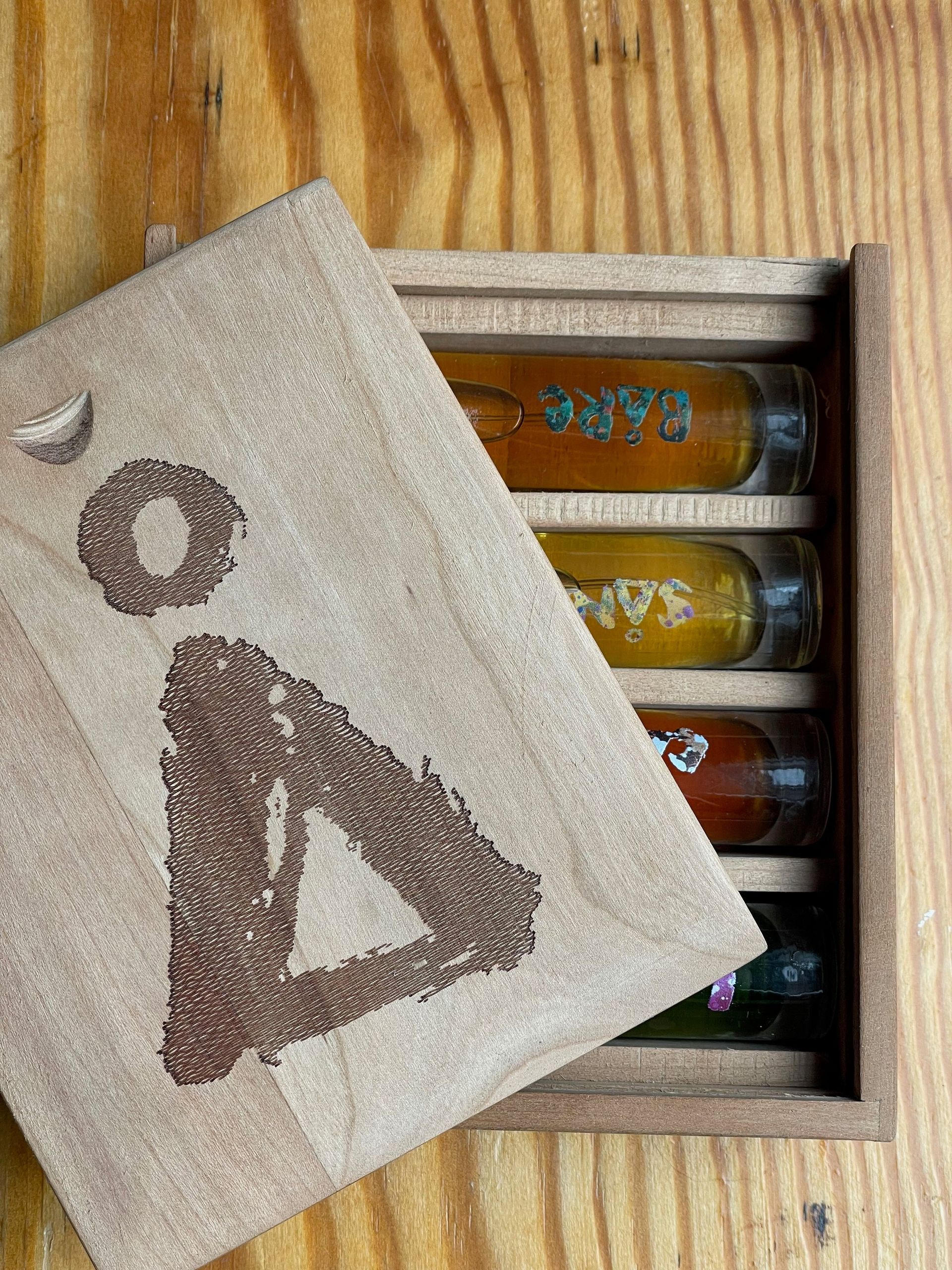 A wooden box filled with bottles of various perfumes on a wooden table.