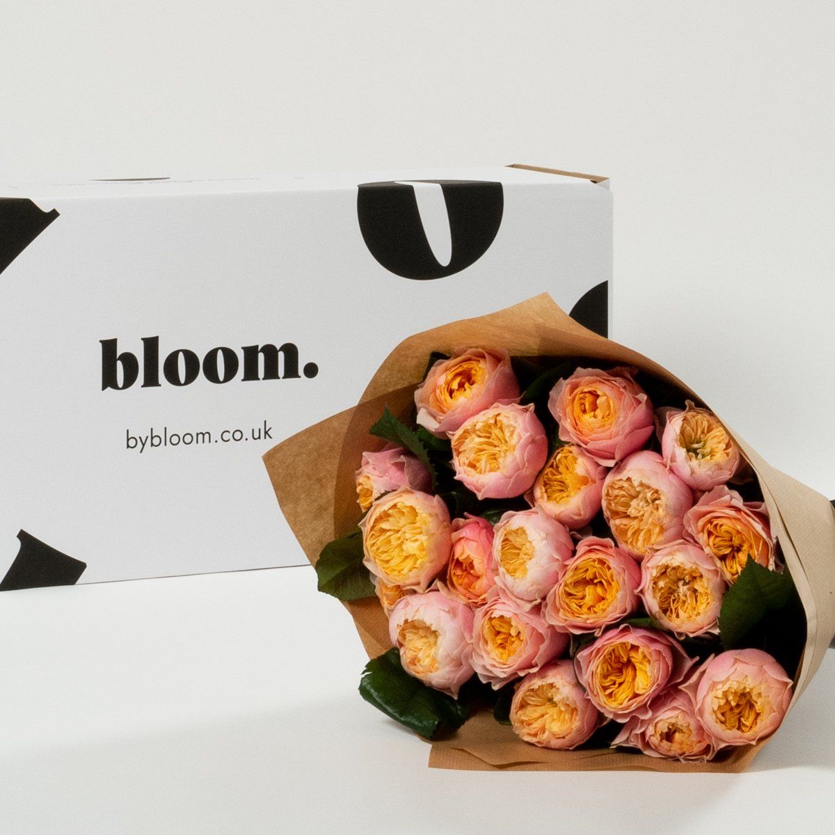 A bouquet of pink flowers next to a box that says bloom