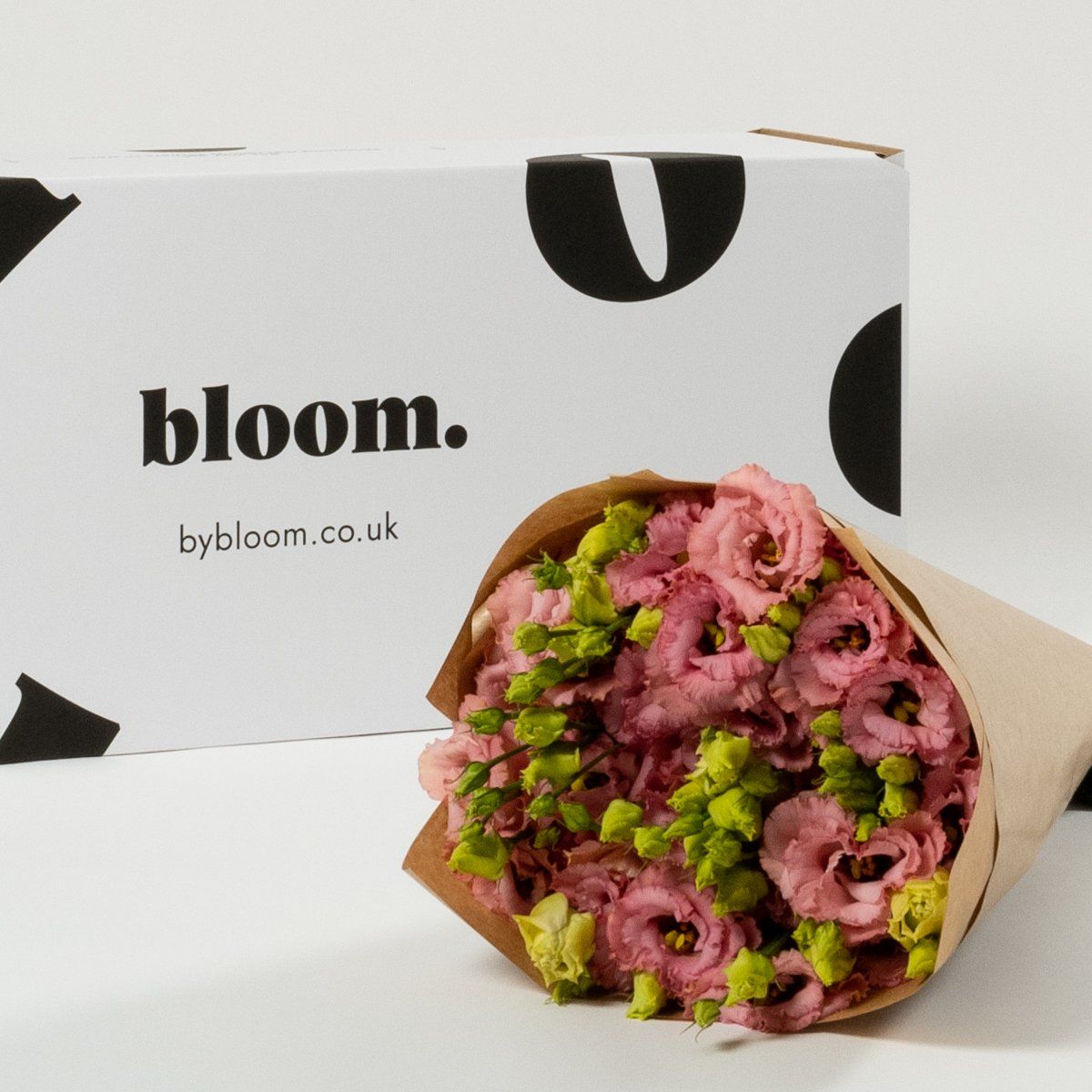 A bouquet of pink flowers next to a box that says bloom