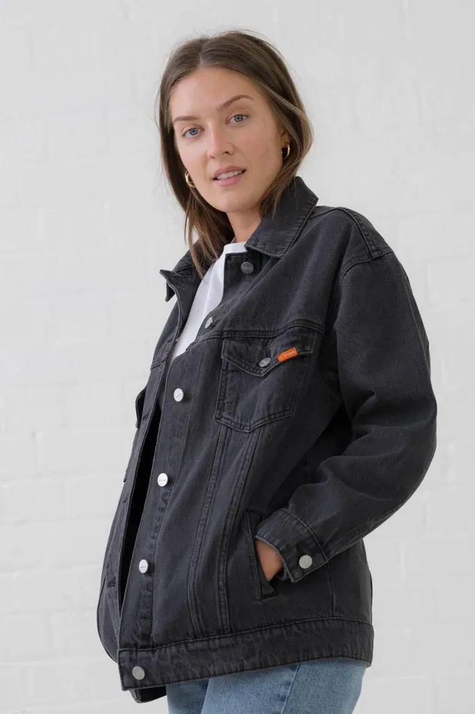 A woman is wearing a black denim jacket and jeans.