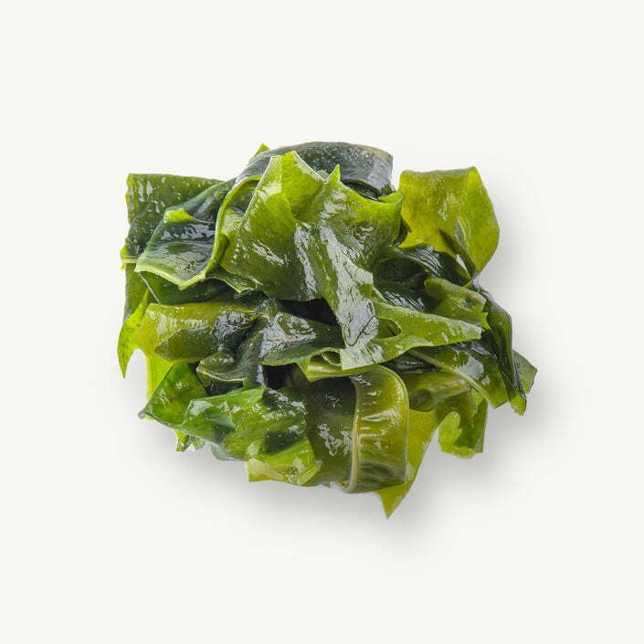 A close up of a pile of seaweed on a white background.