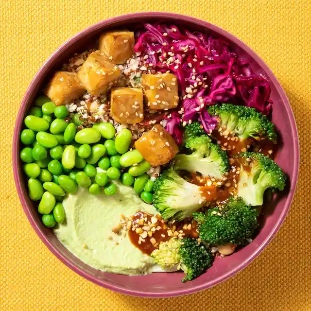 A bowl filled with broccoli , peas , cabbage , and tofu.