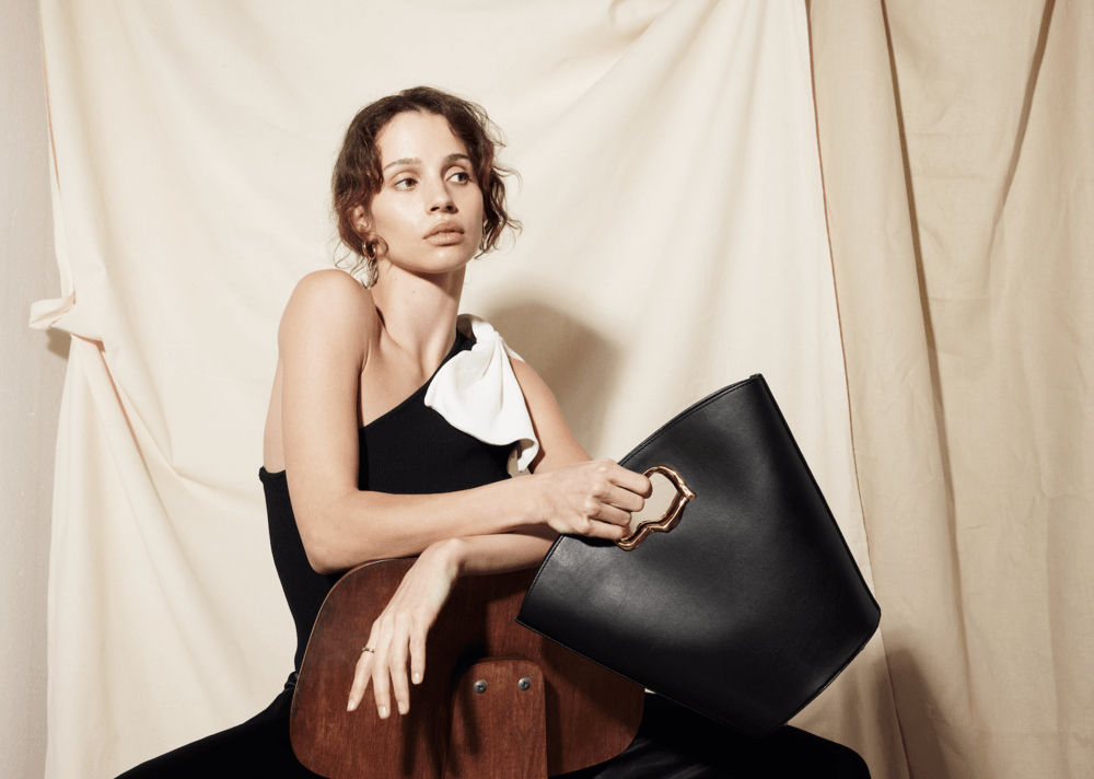 A woman is sitting on a chair holding a black bag.