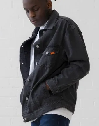 A man wearing a black denim jacket and blue jeans