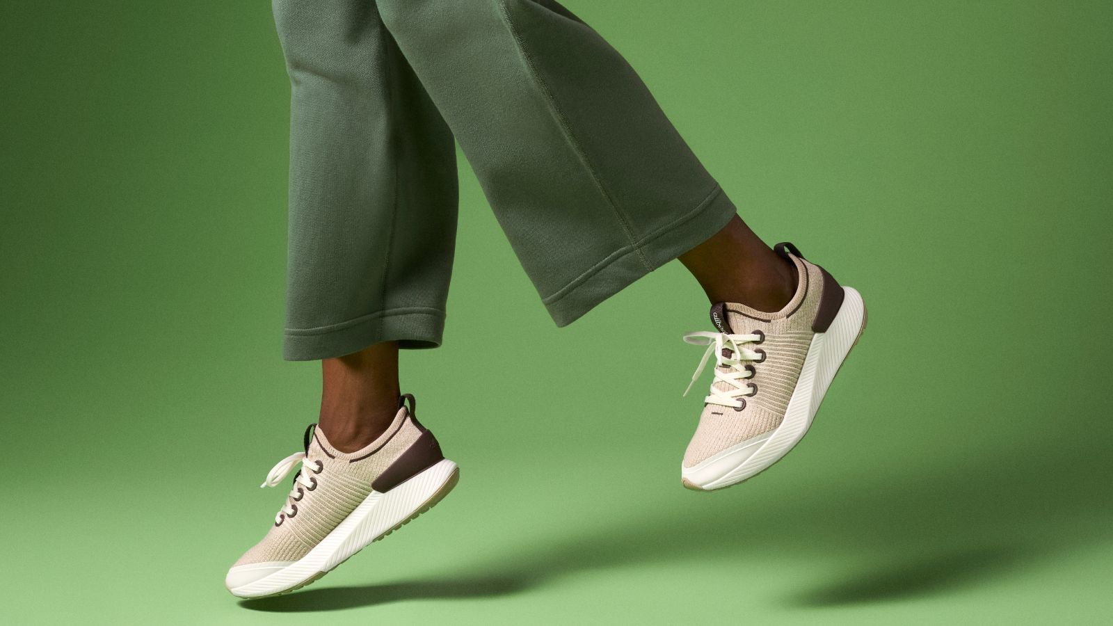 A person is wearing a pair of sneakers on a green background.