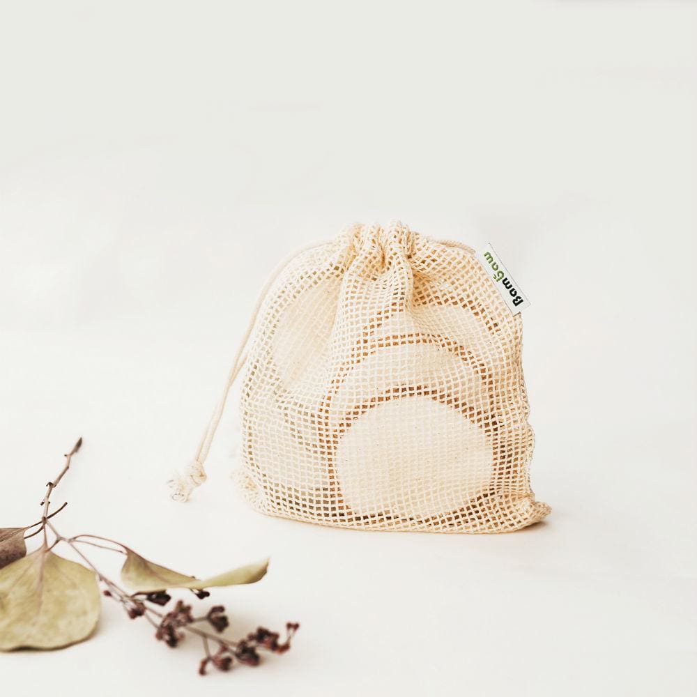 A bag of cotton pads is sitting on a table next to a flower.