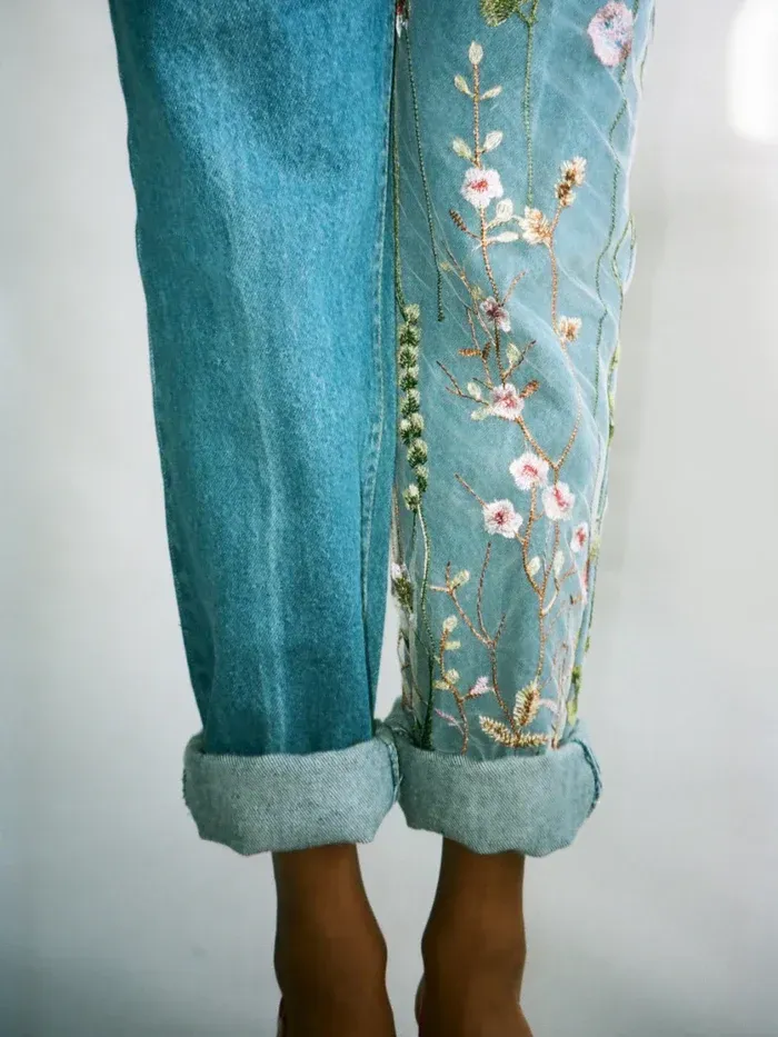 a person wearing a pair of jeans with flowers embroidered on them
