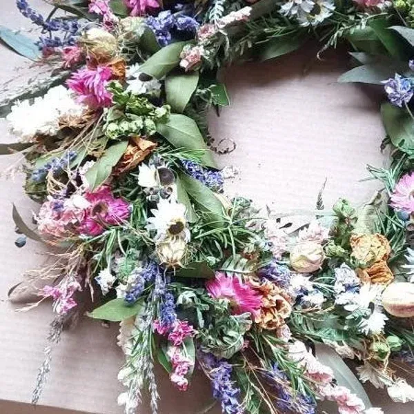 A wreath with purple and pink flowers and green leaves