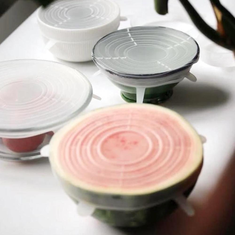 A bowl of watermelon is sitting on a table with other bowls and lids