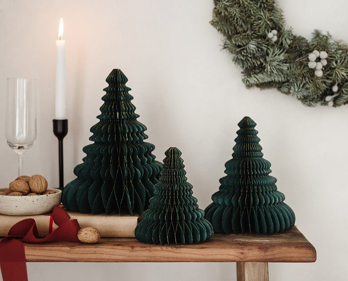 Three paper christmas trees are sitting on a wooden table