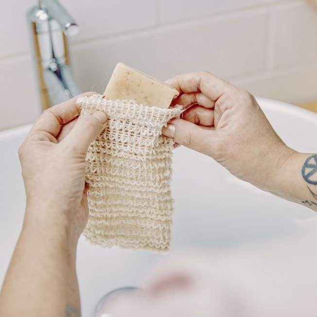 A person is holding a piece of soap in a knitted soap pouch