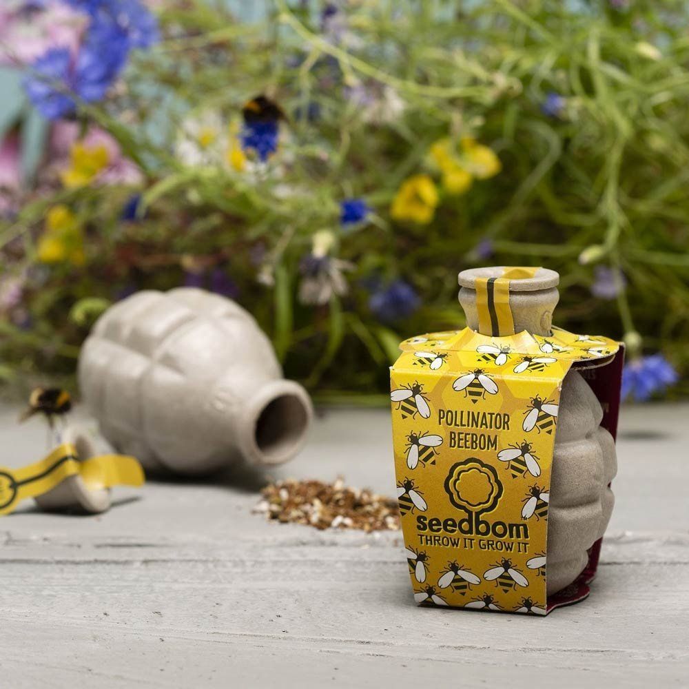 A bottle of seedbomb is sitting on a table with flowers in the background.