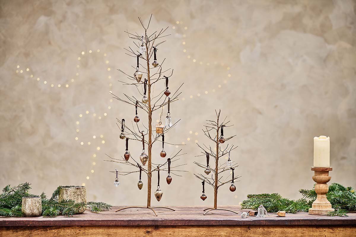 Two metal christmas trees are sitting on top of a wooden table.