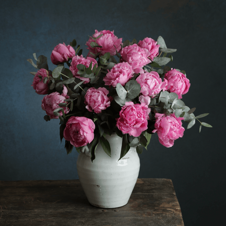 A vase filled with pink flowers is sitting on a wooden table.