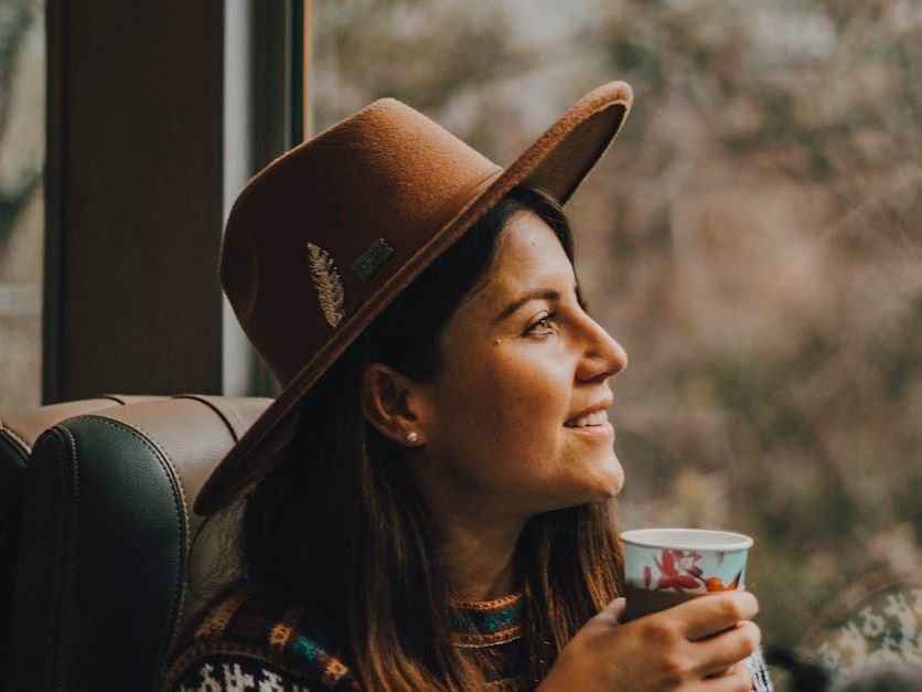 happy woman sitting with a coffee on the train