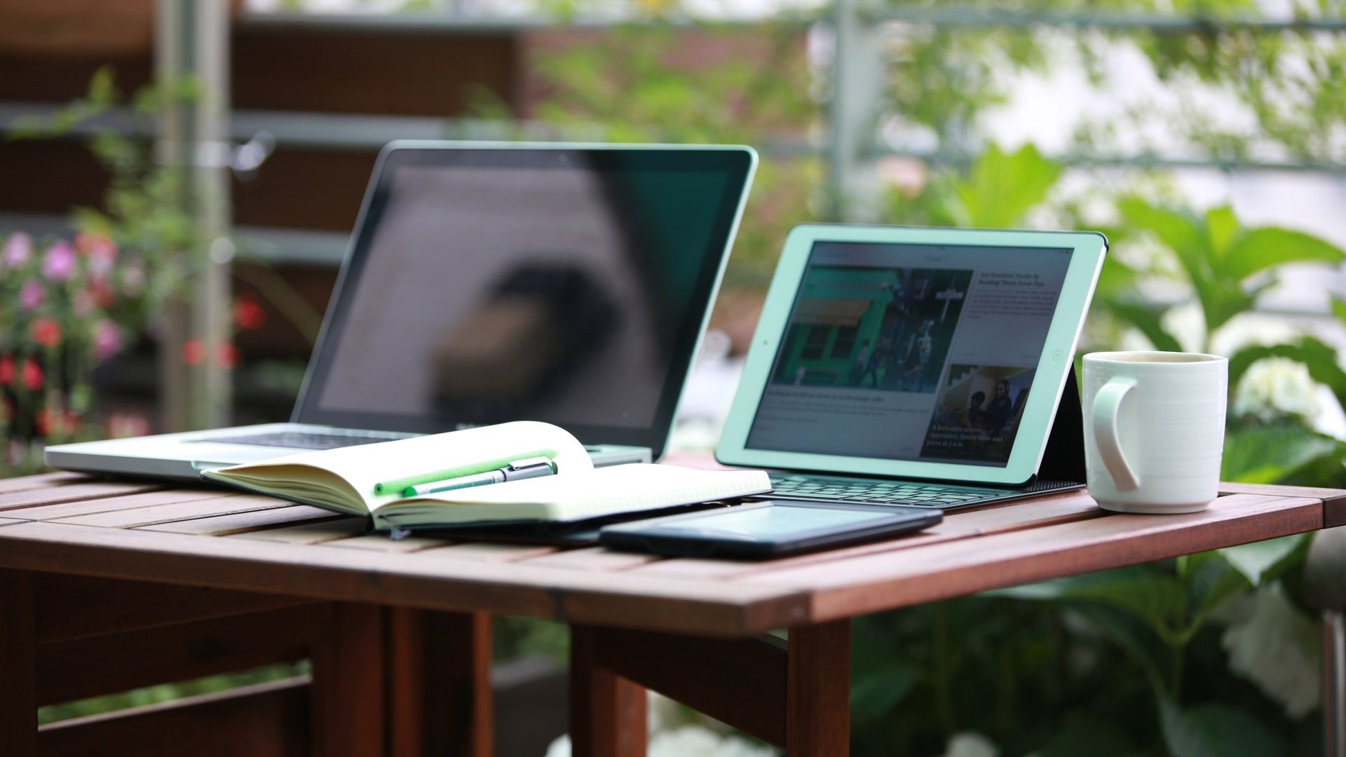 a laptop and a tablet are on a table outside