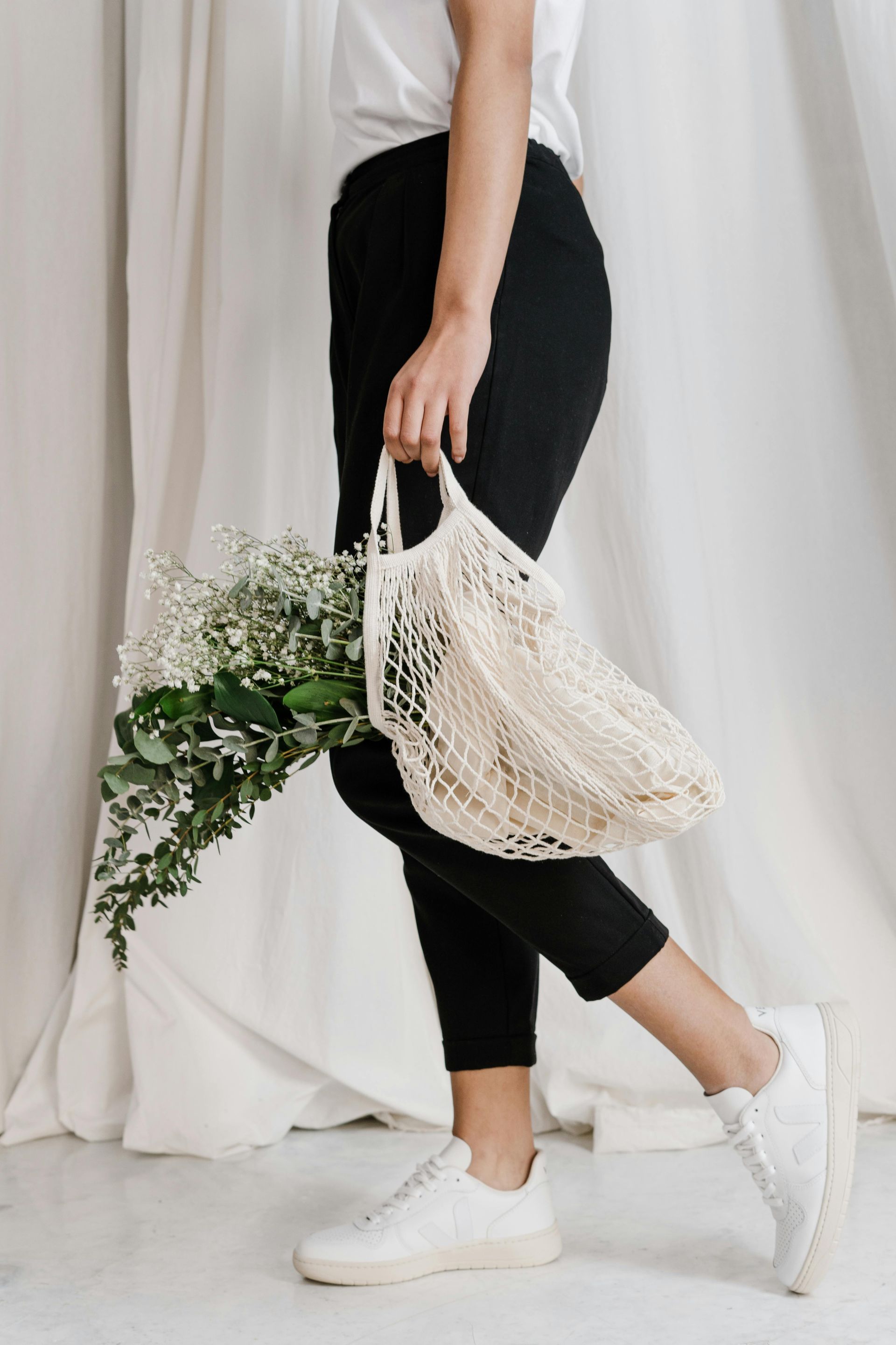 A woman is holding a bag of flowers in her hand.