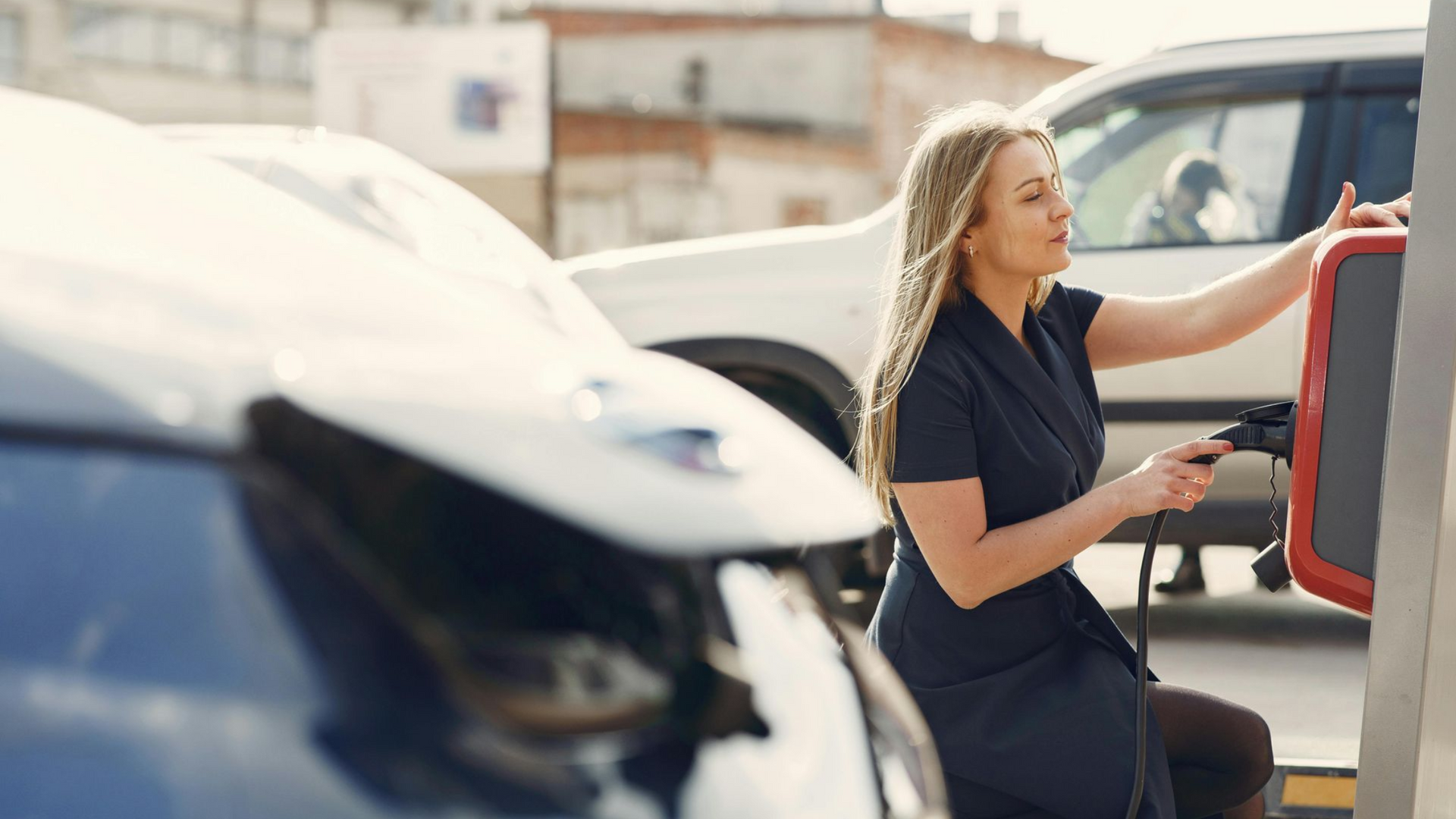 Heat pump unit outside a building, surrounded by greenery. Gray and black.