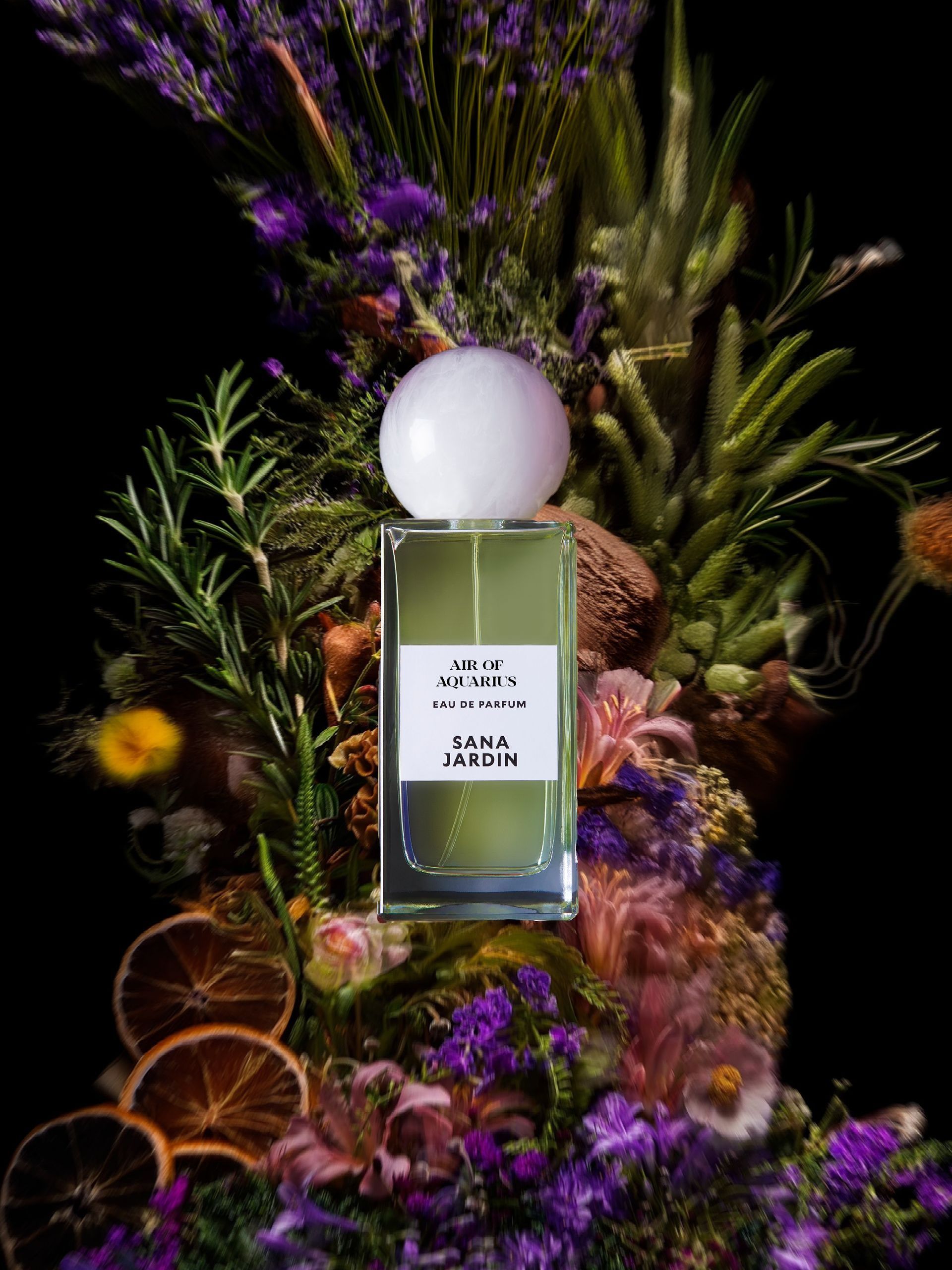 four bottles of perfume from Sana Jardin are sitting on top of rocks on a table .