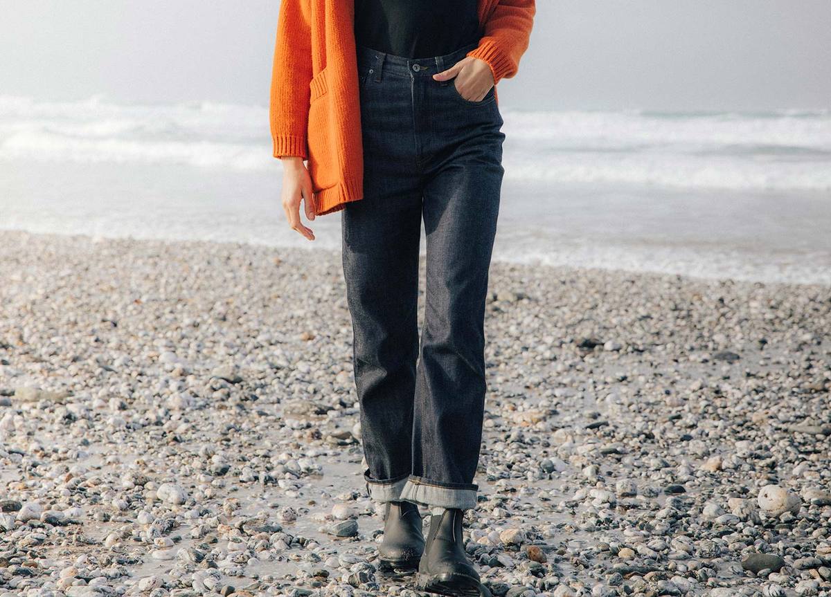A woman is walking on a rocky beach near the ocean.