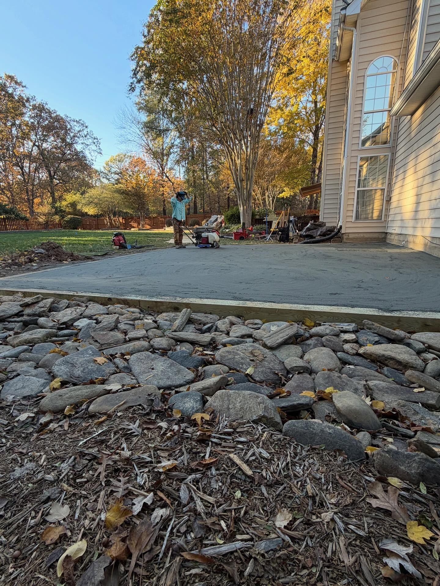 Stone path leading to a courtyard with trees, benches, and a building in autumn sunlight