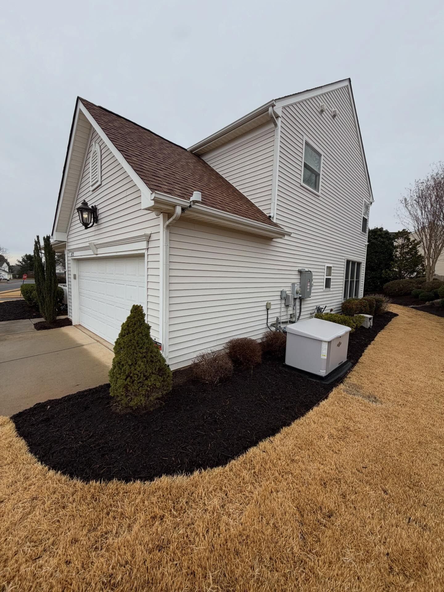 White two-story suburban house with garage, white siding, and landscaped front yard on a cloudy day