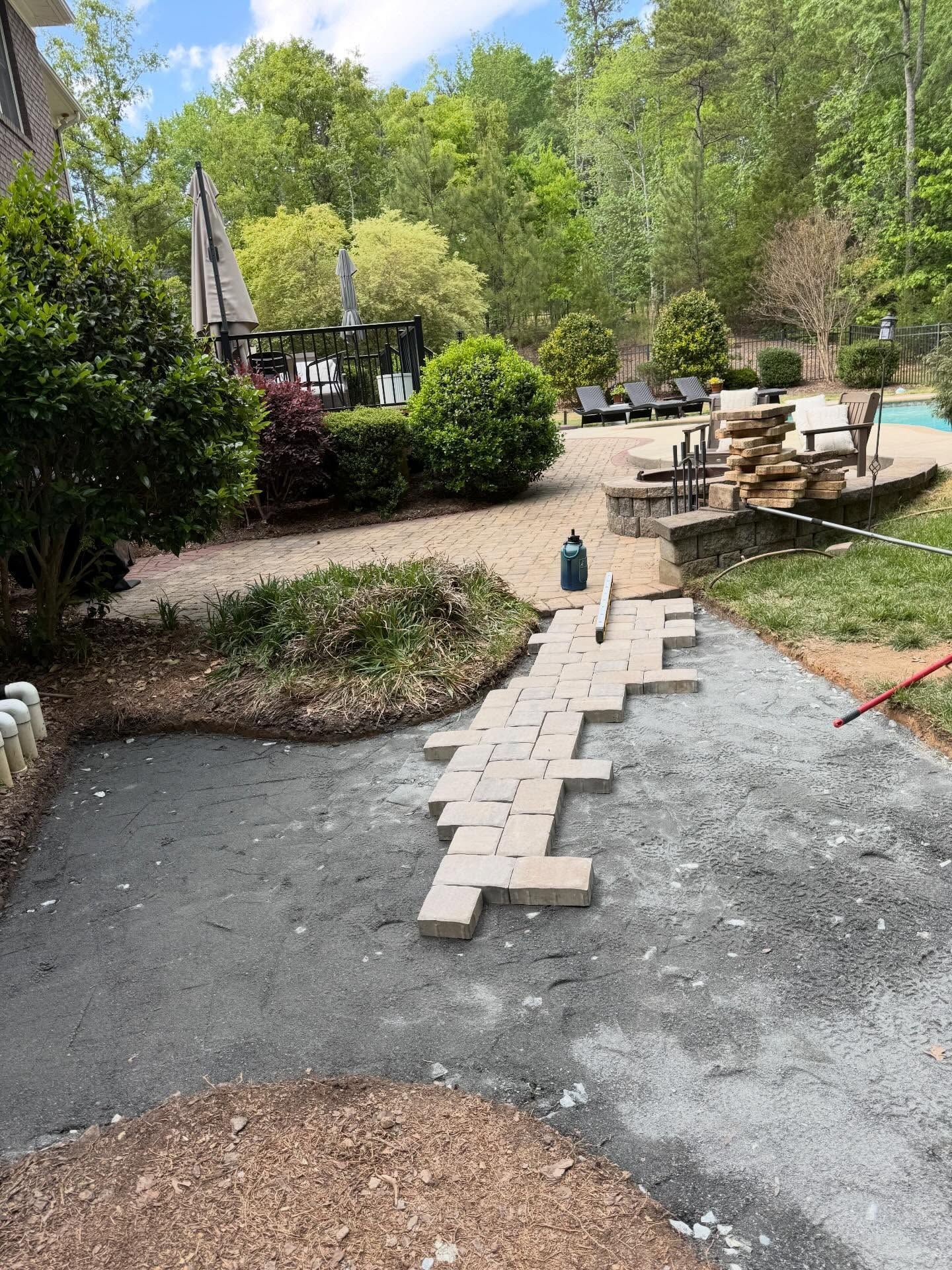 Gravel garden path under construction with stepping stones, trees, and a picnic table in the background