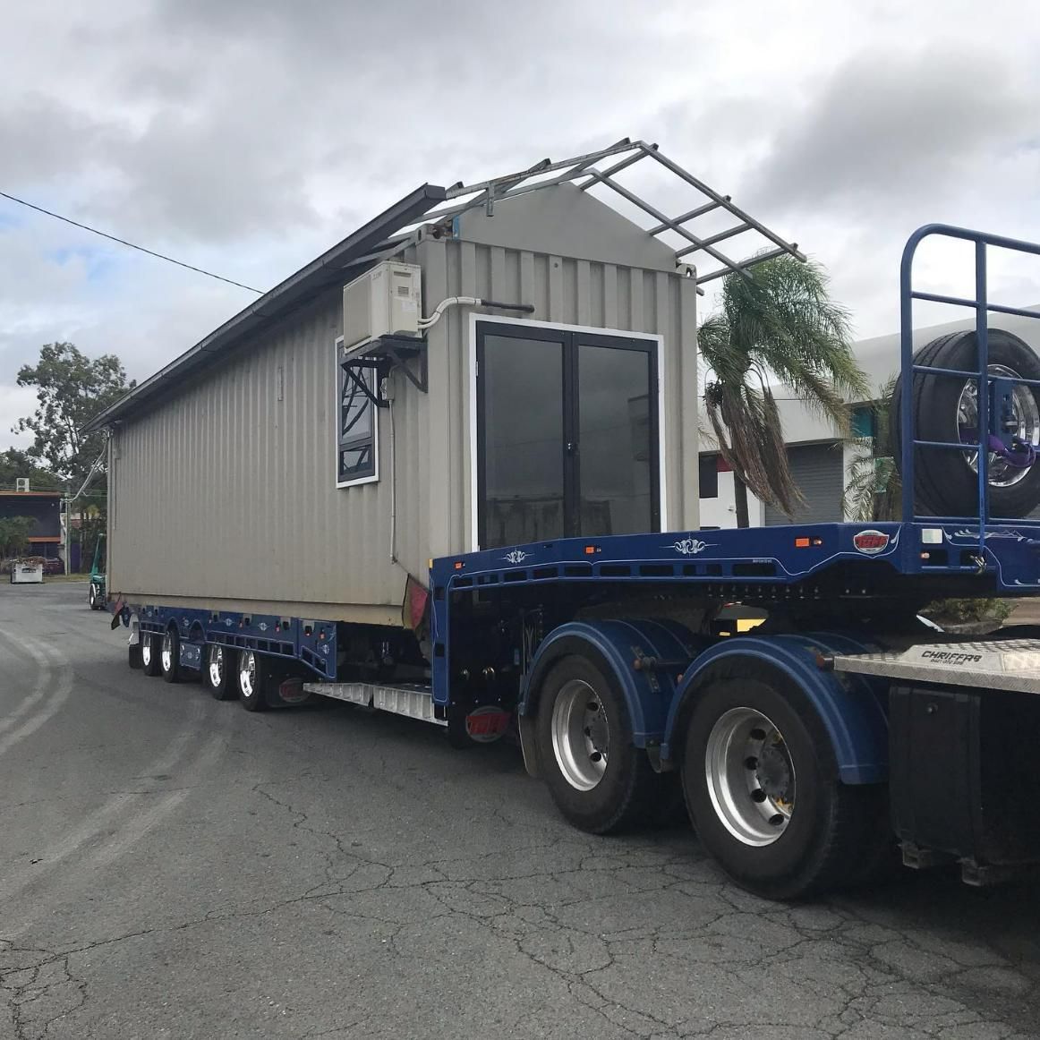A Trailer with A Shed on It Is Parked on The Side of The Road — Mick's Towing Service Pty Ltd in Carrara, QLD