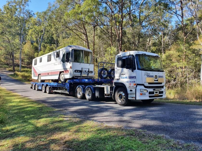 A Truck Is Carrying a Rv Down a Road — Mick's Towing Service Pty Ltd in Carrara, QLD