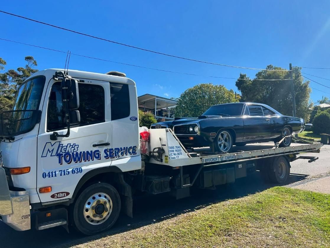 A Towing Truck with A Car on The Back Is Parked on The Side of The Road — Mick's Towing Service Pty Ltd in Carrara, QLD