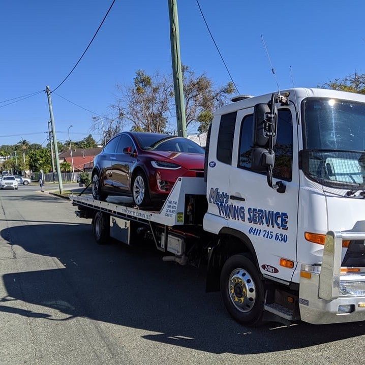 A Tow Truck with A Red Car on The Back of It — Mick's Towing Service Pty Ltd in Carrara, QLD