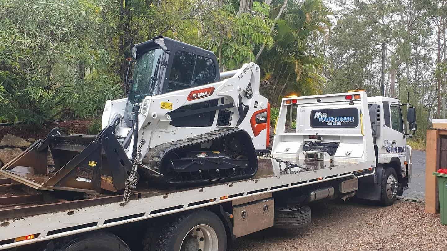 A Bulldozer is Being Towed by a Tow Truck — Mick's Towing Service Pty Ltd in Carrara, QLD