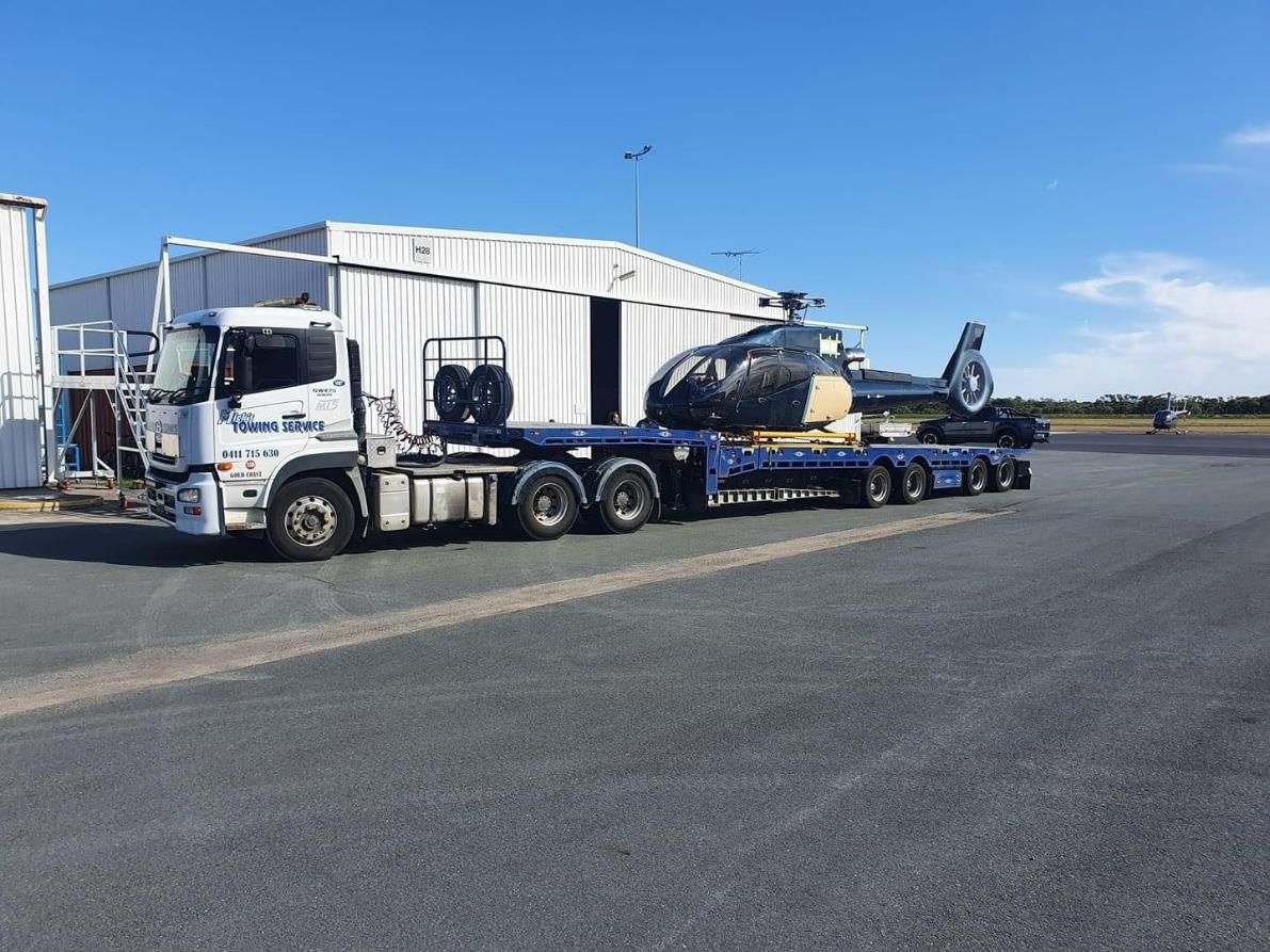 A Truck Is Carrying a Helicopter on A Trailer — Mick's Towing Service Pty Ltd in Carrara, QLD