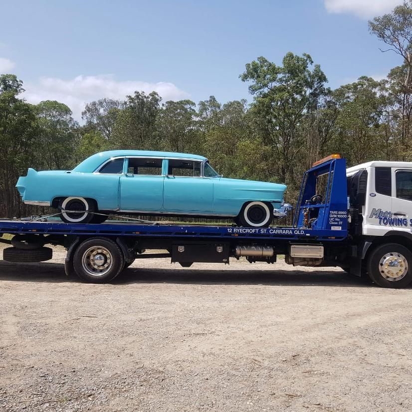 A Blue Car is Being Towed by a Tow Truck — Mick's Towing Service Pty Ltd in Carrara, QLD
