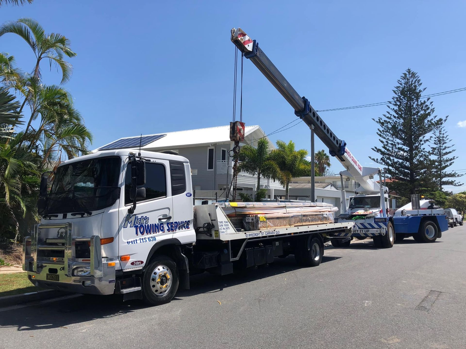 A Tow Truck With a Crane Attached to It is Parked on the Side of the Road — Mick's Towing Service Pty Ltd in Carrara, QLD